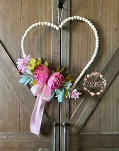 a heart - shaped wreath with flowers and pearls hangs on a barn door in front of a sign that says welcome