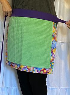 a woman holding onto a purple and green piece of cloth