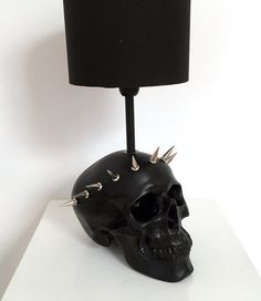 a black skull lamp with spikes on it's head is sitting on a white surface