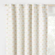 a white curtain with gold polka dots on it in front of a window sill