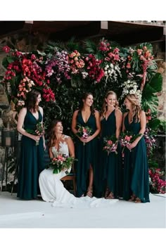 a group of women standing next to each other in front of a flower covered wall