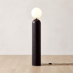 a lamp that is on top of a wooden floor in front of a white wall