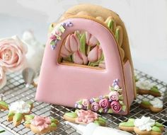 there is a cake shaped like a letter with flowers on the front and side, along with other decorated cookies