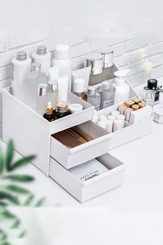 an open drawer with cosmetics and other items in it on a white table next to a brick wall