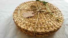 a woven basket with a tag on it sitting on a white tablecloth covered table