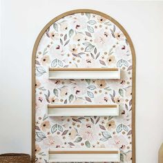 an arched window with floral wallpaper on the side and shelves in front of it