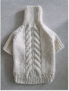 the sweater is knitted in white yarn and has a cabled design on it