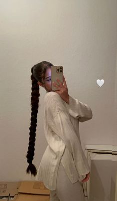 a woman taking a selfie in front of a mirror with her hair pulled back