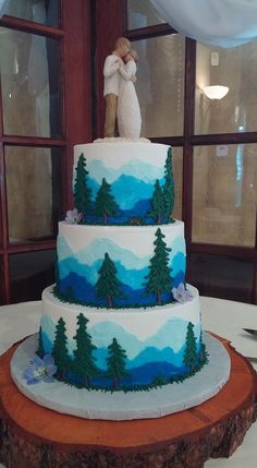 a three tiered cake with trees and mountains on it