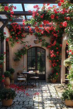 an outdoor dining area with potted plants and red flowers on the wall above it