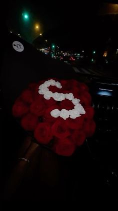 a bouquet of red roses sitting on top of a car dashboard with the letter s painted on it