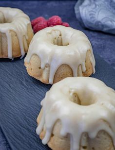 three bundt cakes with white icing and raspberries on a blue plate