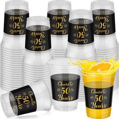 plastic cups filled with orange juice and topped with gold foil lettering on the side, surrounded by clear cups