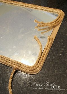 a mirror with rope around it sitting on a table