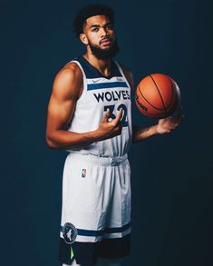 a man holding a basketball in his right hand and looking at the camera with an intense look on his face