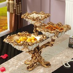 three tiered trays filled with fruit on top of a table next to a window