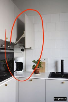 an orange circle is in the middle of a kitchen counter top with white cabinets and black appliances