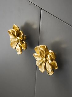 two gold flowers on a gray wall