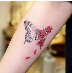 a woman's arm with a butterfly and roses tattoo on the left side of her arm