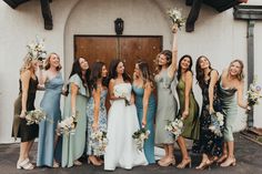 a group of women standing next to each other in front of a building holding bouquets