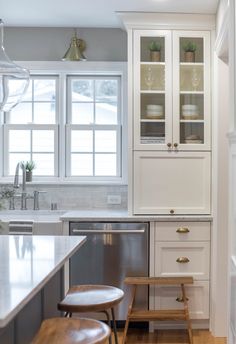 a kitchen with white cabinets and wooden stools