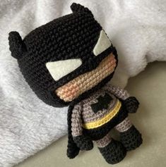 a crocheted batman amigurt sitting on top of a white bed sheet