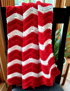 a red and white crocheted blanket sitting on top of a chair