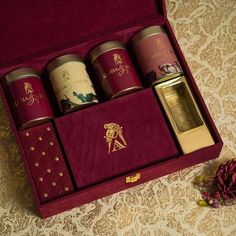 an open red box with four different types of perfumes in it on a table