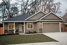 a gray house with two car garages in the front yard