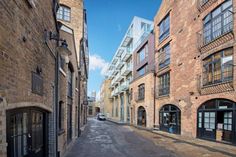 an empty street with brick buildings on both sides and cars parked in the alleyway