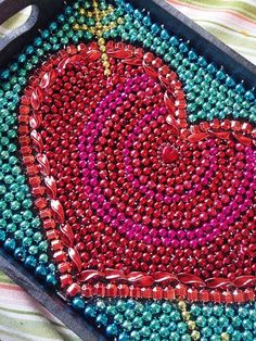 a heart shaped beaded tray sitting on top of a striped cloth covered tablecloth