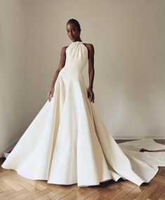 a woman in a white dress standing on a wooden floor