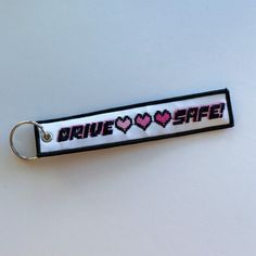 a keychain with the words drive safe printed on it and two hearts in pink