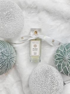 a bottle of perfume sitting on top of a white blanket next to some balls and ornaments