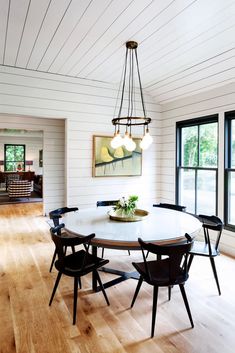 a dining room table with four chairs and a painting on the wall behind it,