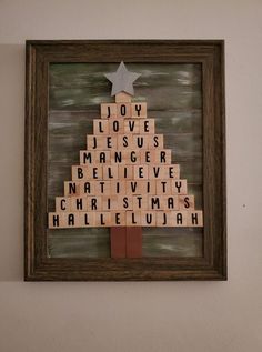 a wooden scrabble christmas tree with words written on it, framed in a wood frame