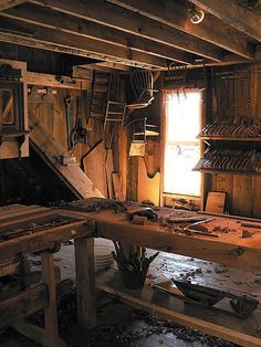 an old wooden room with many items on the floor and in the wall, there is a ladder hanging from the ceiling