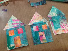 some paper houses are sitting on a table with glue and paint splattered over them