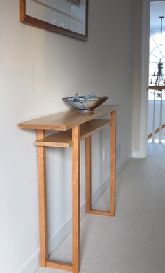 a wooden table with a bowl on it in a living room next to a doorway