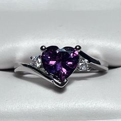 a heart shaped purple diamond ring with three diamonds on the band and two white gold bands