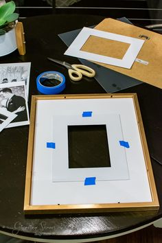 a table topped with pictures and scissors on top of a black table covered in paper