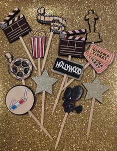 hollywood themed cupcake toppers on a gold glitter background with stars and clapsticks