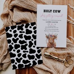 a cow themed baby shower is on display next to a note card and golden scissors