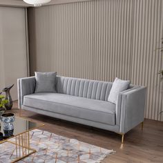 a living room with a couch, coffee table and vases on the wooden floor