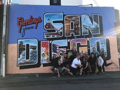 a group of people standing in front of a wall with the words san diego painted on it