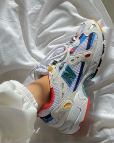 a person's feet wearing white sneakers with colorful accents on the upper part of their shoes