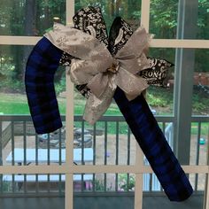 a blue and white ribbon bow hanging from the side of a window sill in front of a glass door