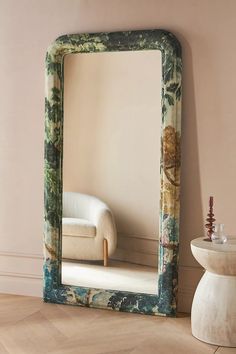 a mirror sitting on top of a wooden floor next to a white chair