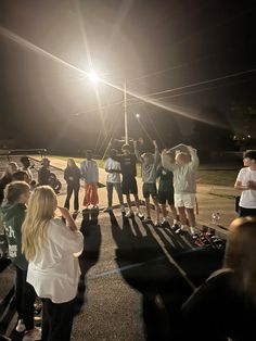 a group of people standing on top of a parking lot next to each other at night