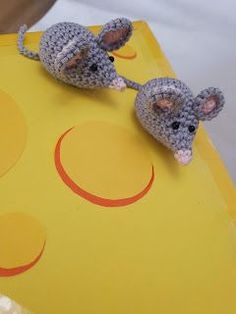 two crocheted mouses sitting on top of a yellow board next to each other